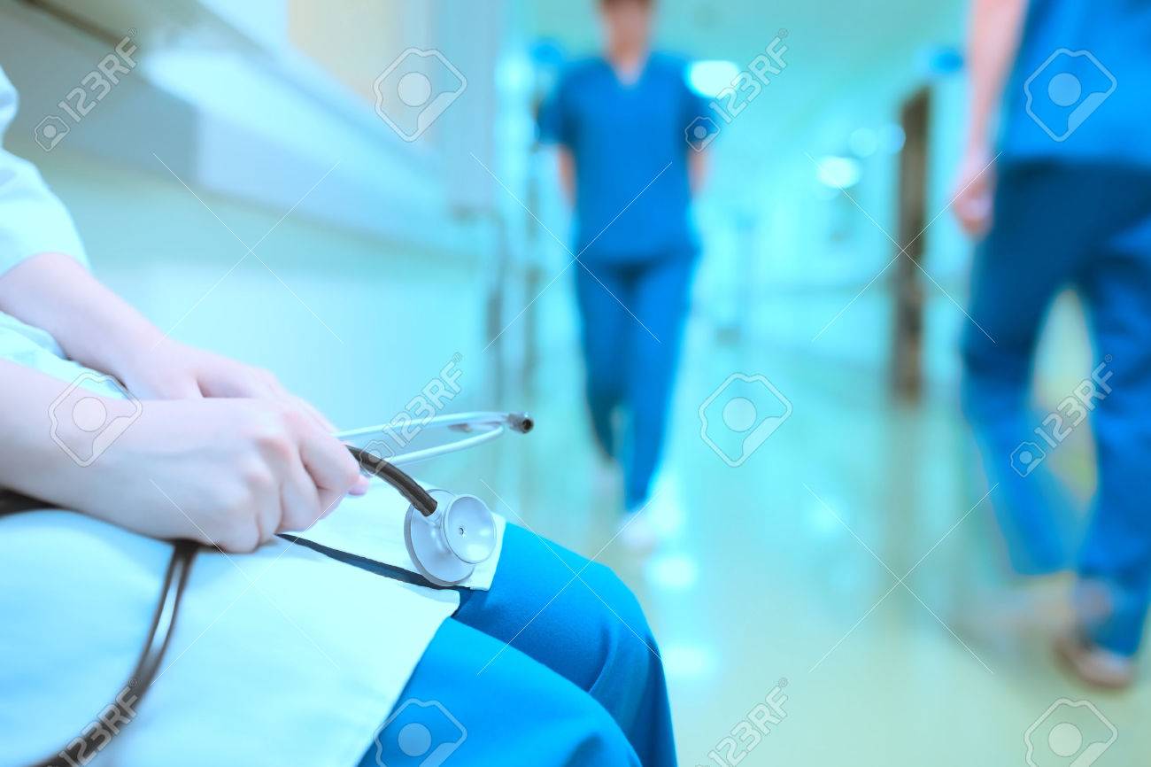 Tired doctor in hospital hall. - 54221141 Tired doctor in hospital hall. - 54221141
