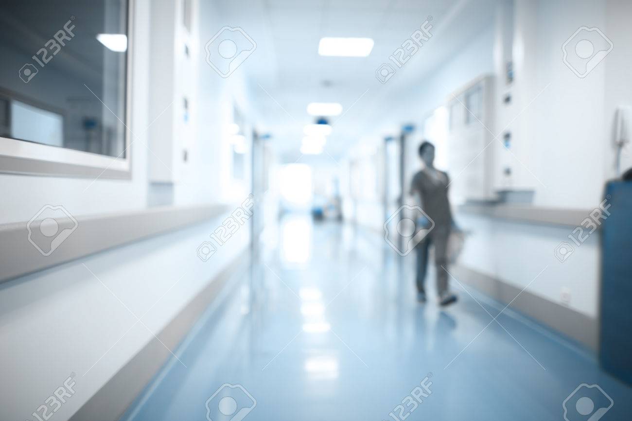 Walking medical person in hospital hall, unfocused background. - 63955284 Walking medical person in hospital hall, unfocused background. - 63955284