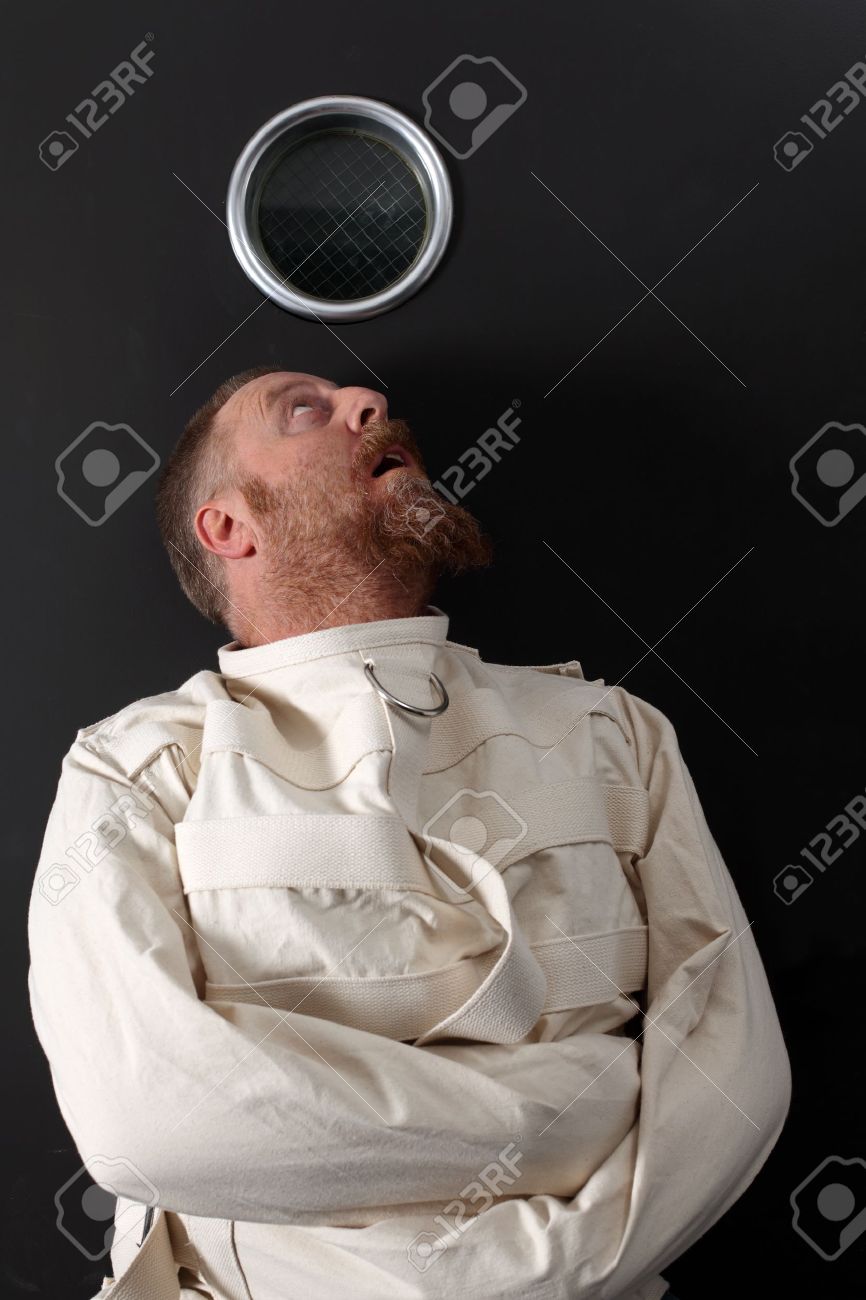 Photo of an insane man in his forties wearing a straitjacket crouched below the window of his cell. - 11873038 Photo of an insane man in his forties wearing a straitjacket crouched below the window of his cell. - 11873038