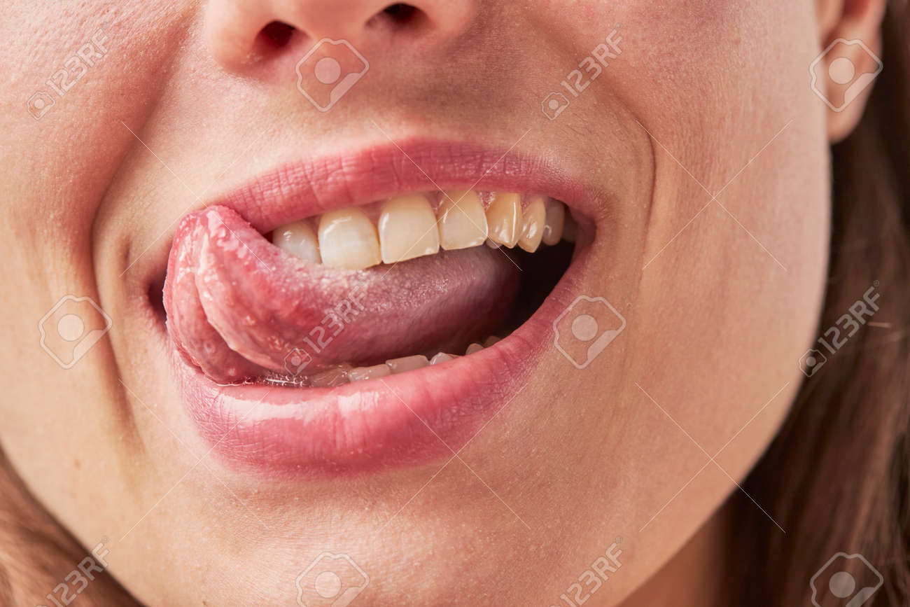 Beautiful young woman leaking teeth with tongue close-up - 165993272 Beautiful young woman leaking teeth with tongue close-up - 165993272