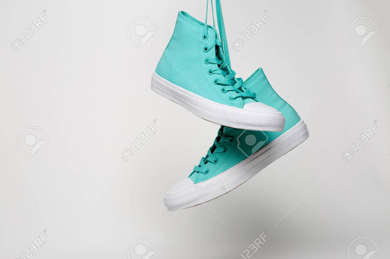Blue Sport shoes hanging on laces on white background