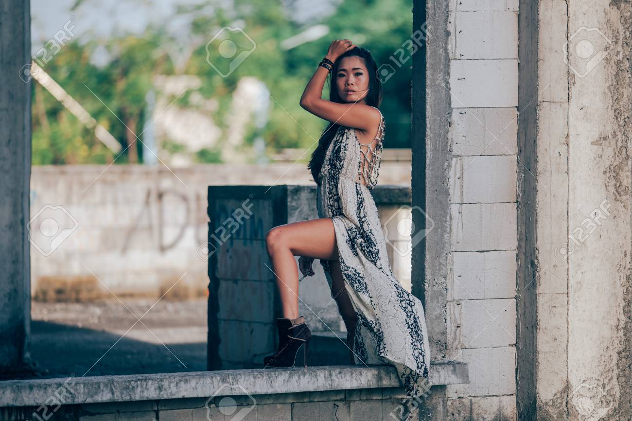 コンクリートブロックの上に立って 彼女の髪に触れるカメラを見てアジアの中国のファッションモデルの女の子 の写真素材 画像素材 Image