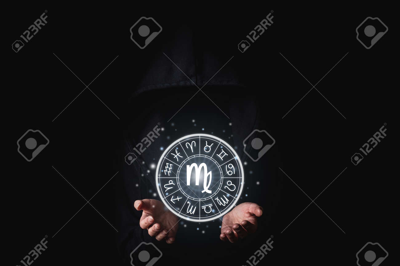 A woman in a black mantle with her palms holds the glowing astrological signs of the zodiacs on a black background. - 171756602 A woman in a black mantle with her palms holds the glowing astrological signs of the zodiacs on a black background. - 171756602