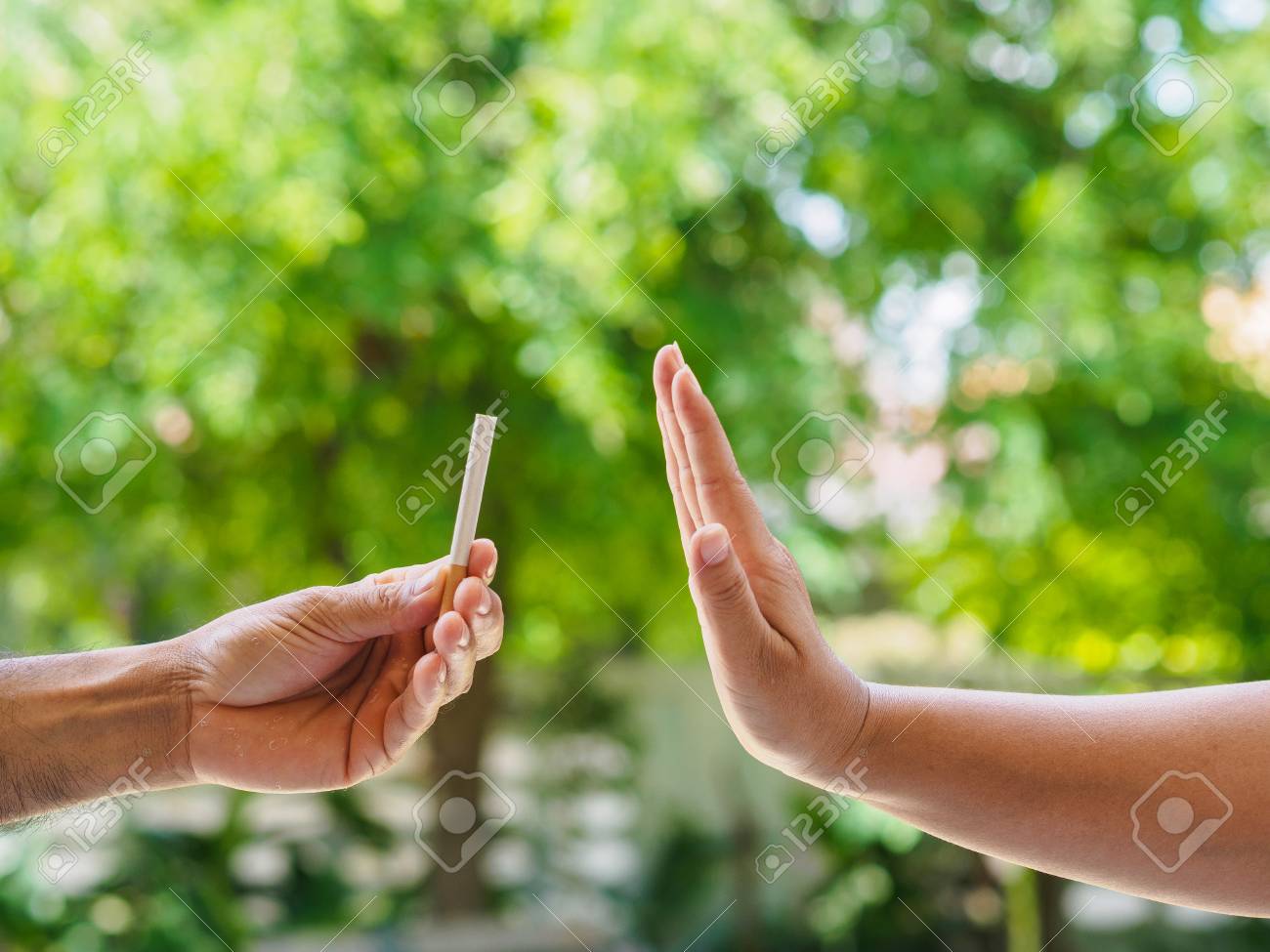 No smoking. Close up of male hands holding cigarettes and proposing it to person. The human arm is gesturing with refusal on bokeh background. - 101884789 No smoking. Close up of male hands holding cigarettes and proposing it to person. The human arm is gesturing with refusal on bokeh background. - 101884789