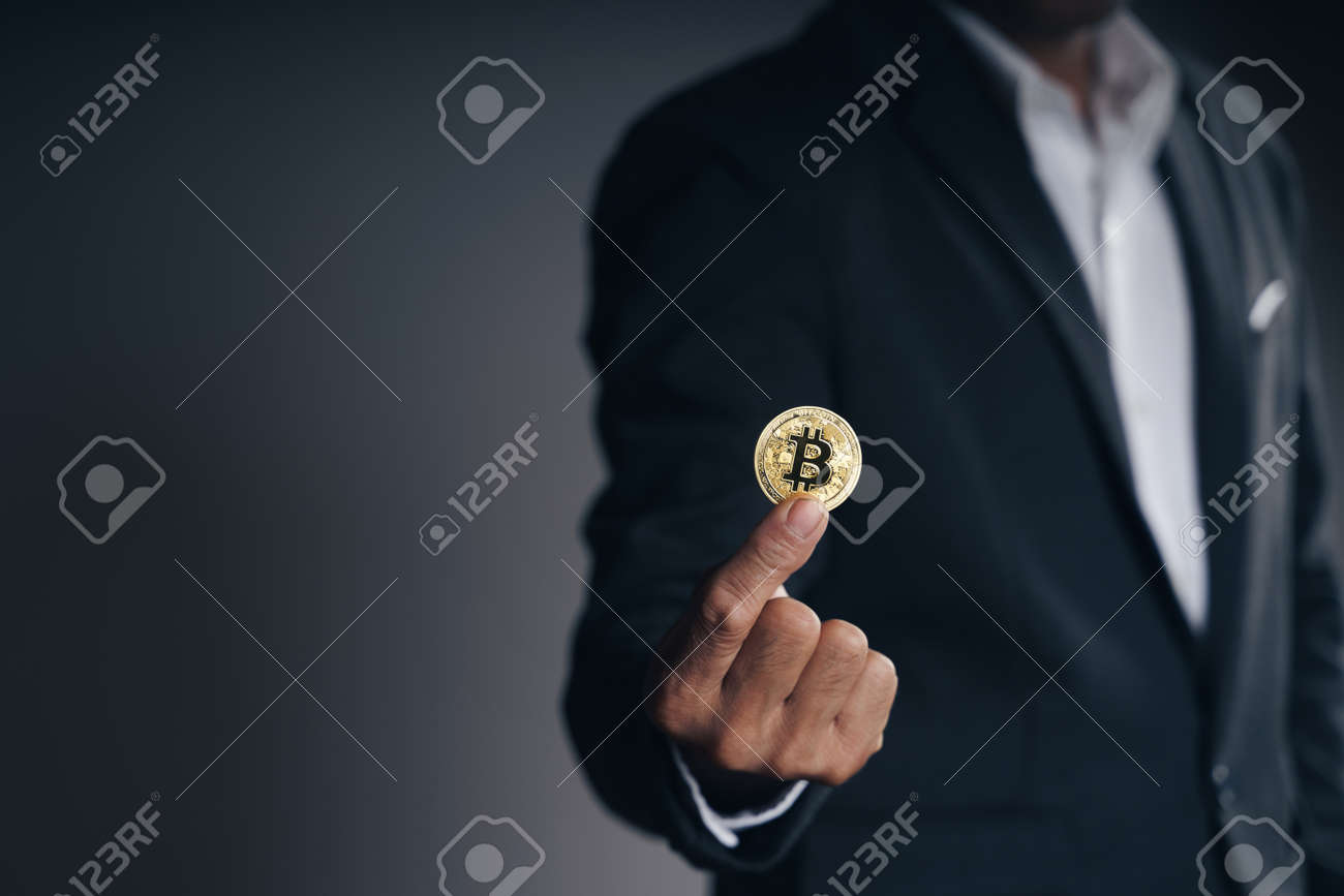 Handsome Investor Businessman in black suit holding a golden bitcoin on dark background, trading, Cryptocurrency, Digital virtual currency, alternative finance and investment Concept. - 172185713 Handsome Investor Businessman in black suit holding a golden bitcoin on dark background, trading, Cryptocurrency, Digital virtual currency, alternative finance and investment Concept. - 172185713