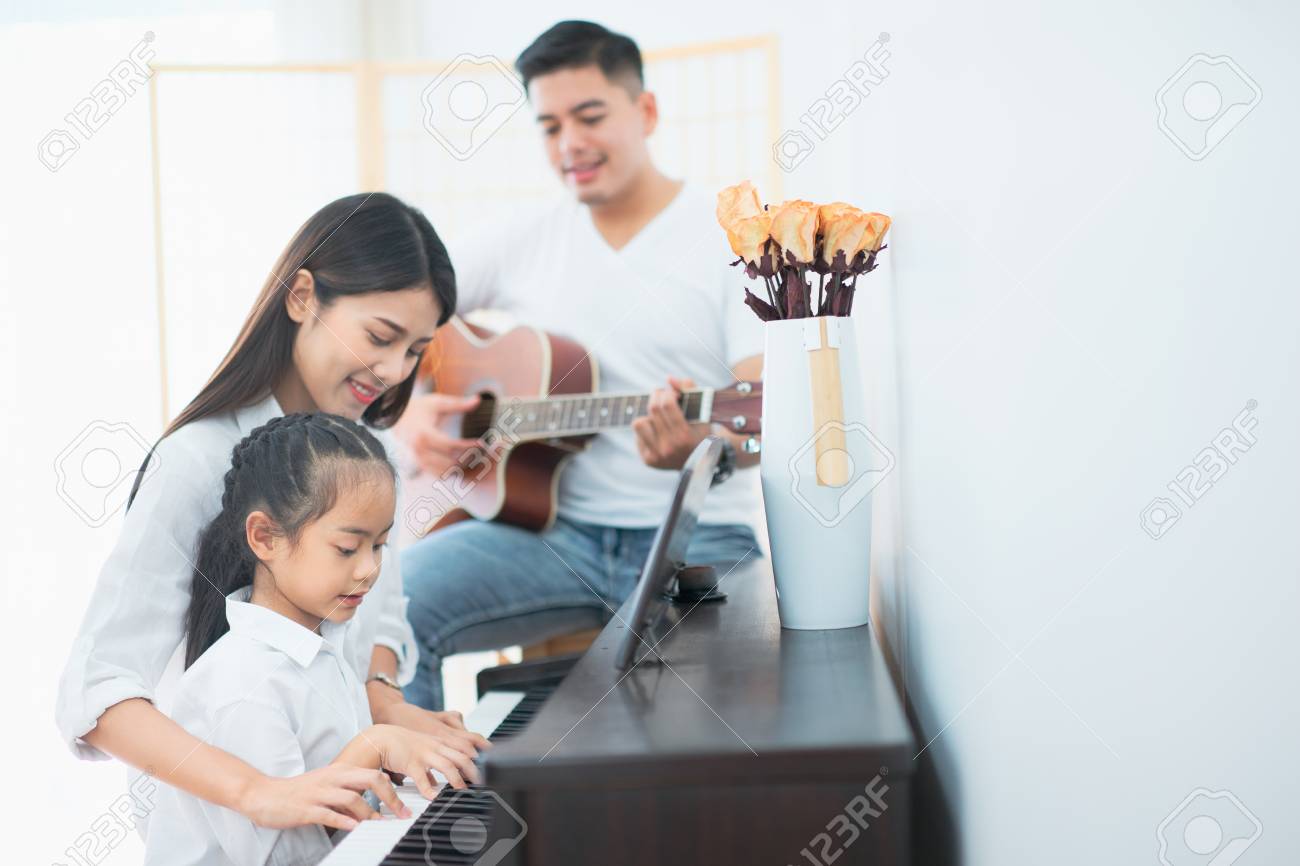 Asian family, Mother and daughter playing piano,Father playing guitar in family band at home, Concept for family relationship - 104004087 Asian family, Mother and daughter playing piano,Father playing guitar in family band at home, Concept for family relationship - 104004087