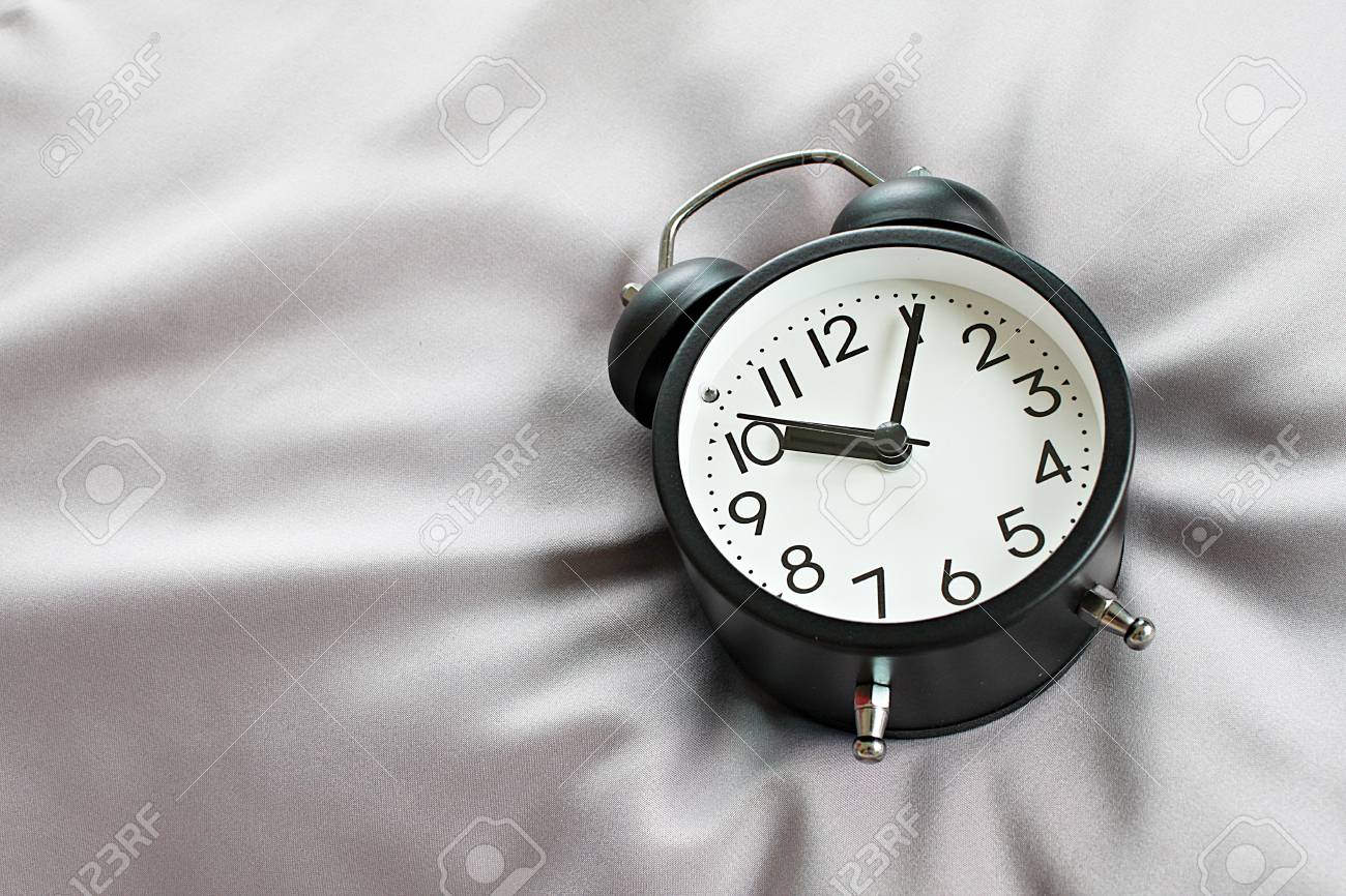 Still life, business deadline, meeting, time management, savings time, relax, weekend or holiday concept concept : Top view of black retro alarm clock on bed in morning, ready for adding or mock up - 126599879 Still life, business deadline, meeting, time management, savings time, relax, weekend or holiday concept concept : Top view of black retro alarm clock on bed in morning, ready for adding or mock up - 126599879