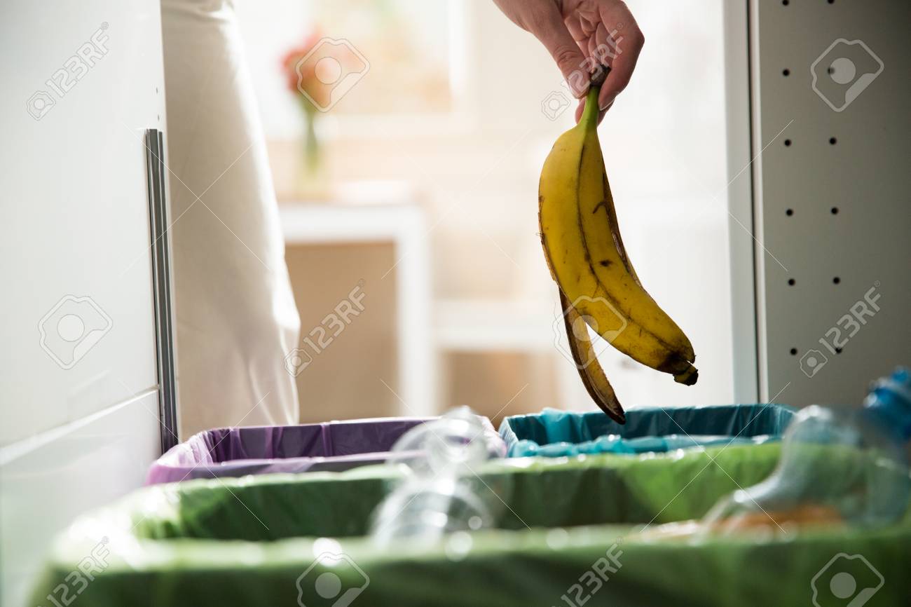 Woman Putting Banana Peel In Recycling Bio Bin In The Kitchen