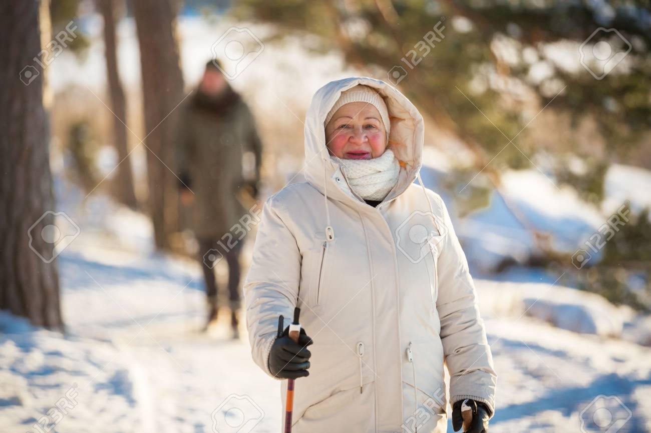 フィンランドのノルディック ウォーキングの冬スポーツ 年配の女性と男性の冷たい森のハイキングします 屋外活動的な人 風光明媚な静かなフィンランドの風景 の写真素材 画像素材 Image