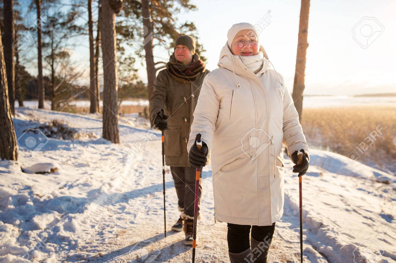 フィンランドのノルディック ウォーキングの冬スポーツ 年配の女性と男性の冷たい森のハイキングします 屋外活動的な人 風光明媚な静かなフィンランドの風景 の写真素材 画像素材 Image