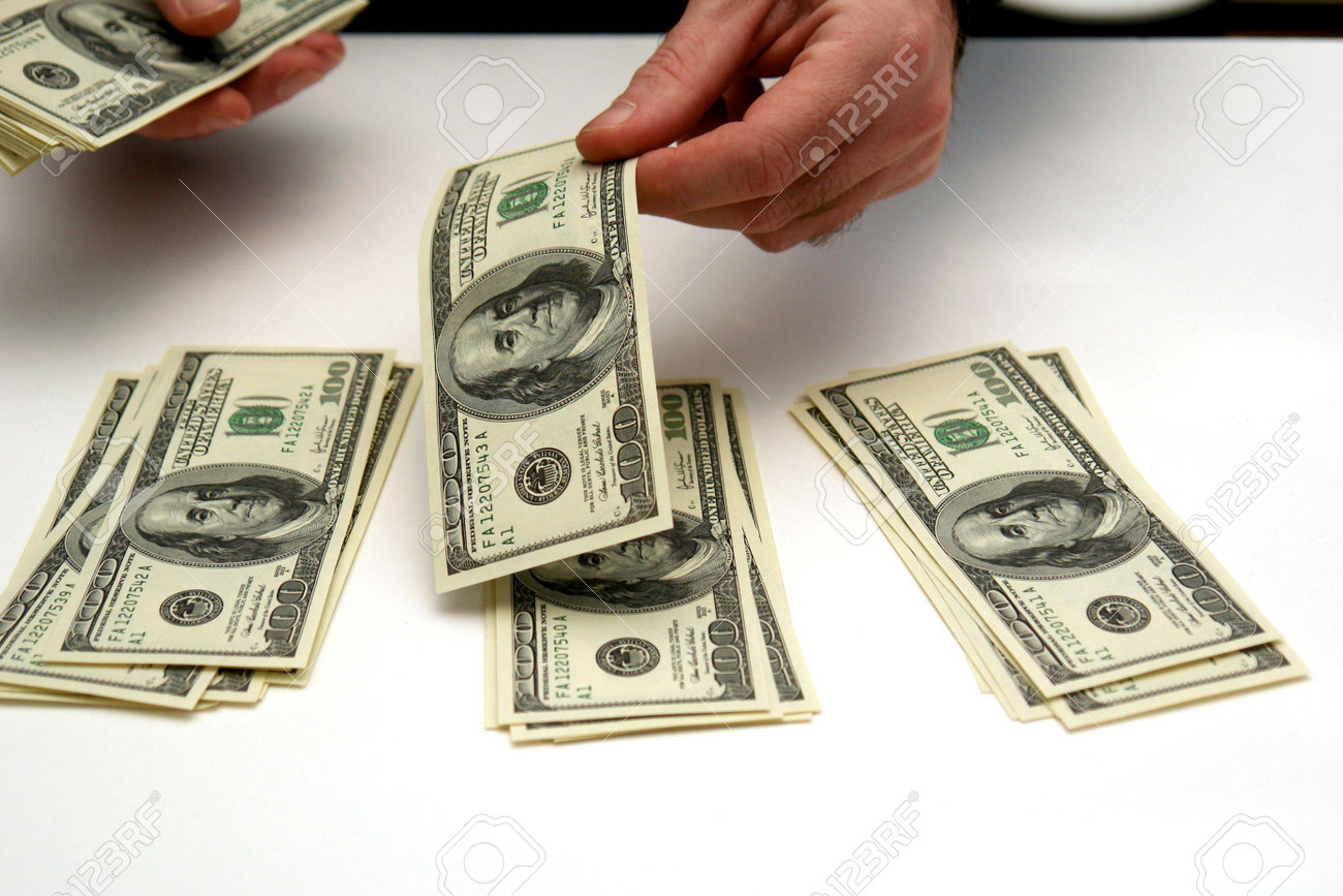 worksheet Counting Dollar Bills man counting out hunderd dollar bills in three stacks on white table