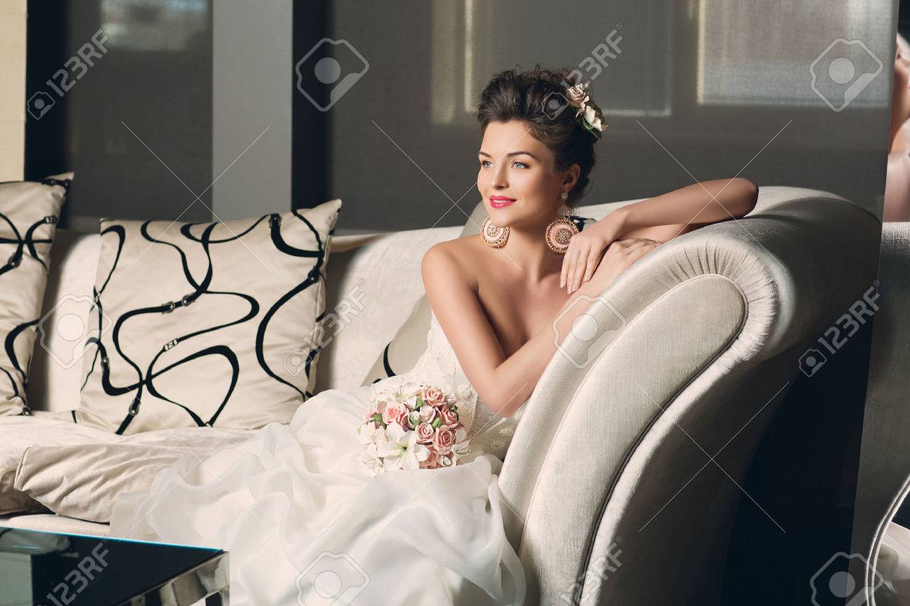 Beautiful young bride in fashionable gown with sitting on sofa. Interior photo. - 41867809 Beautiful young bride in fashionable gown with sitting on sofa. Interior photo. - 41867809
