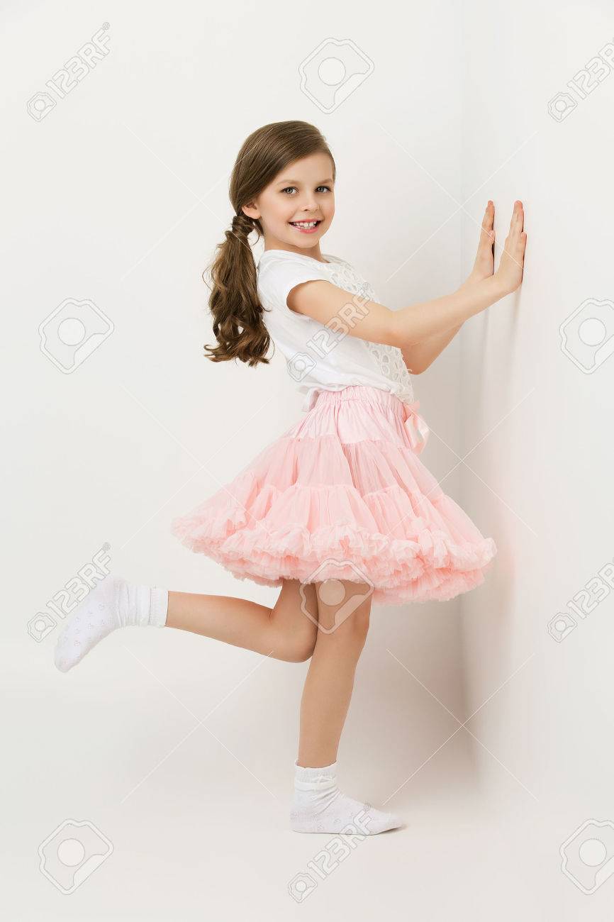 Beautiful little happy girl in tutu skirt standing near white wall - 46427965 Beautiful little happy girl in tutu skirt standing near white wall - 46427965