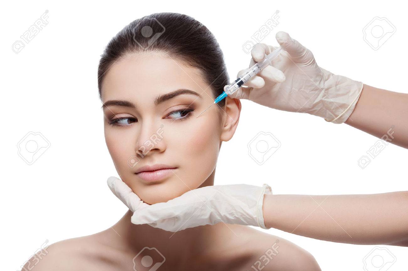 Beautiful young woman gets beauty injection in eye area from sergeant. Isolated over white background. - 47856028 Beautiful young woman gets beauty injection in eye area from sergeant. Isolated over white background. - 47856028