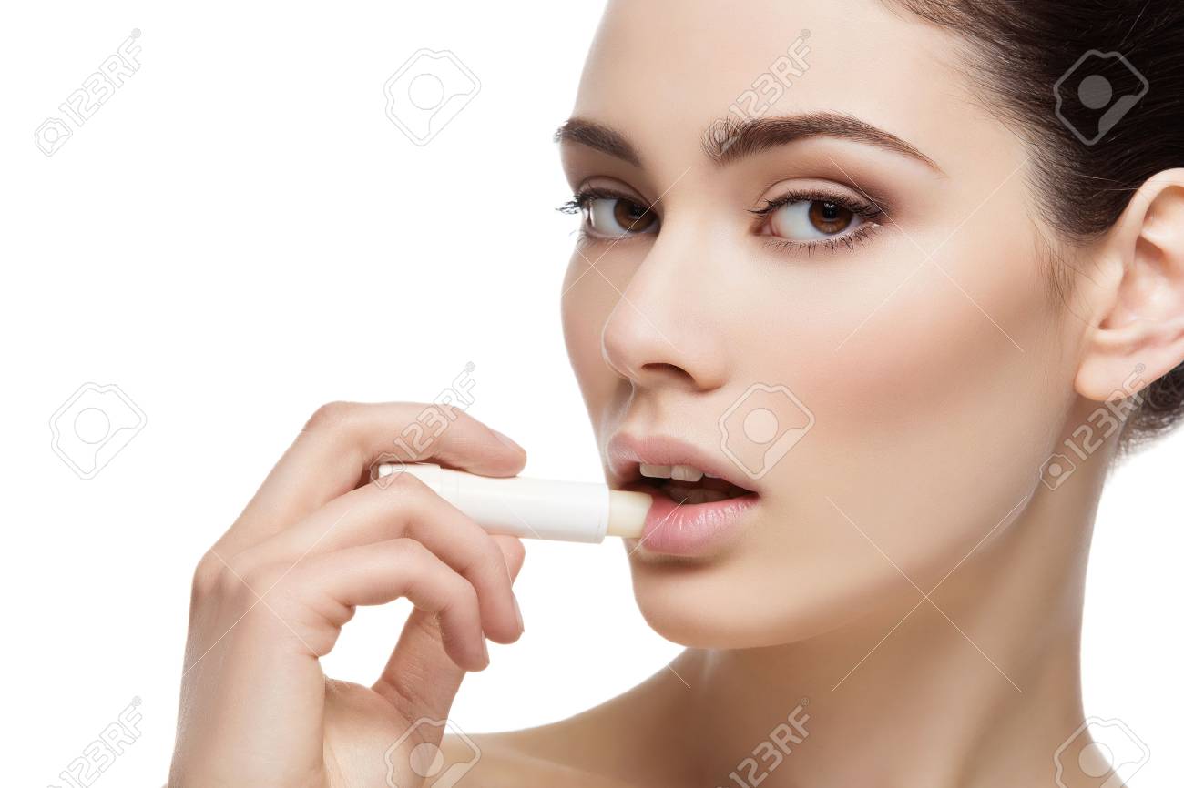 Beautiful young woman applying chapstick to lips. Isolated over white background. Copy space. - 51170135 Beautiful young woman applying chapstick to lips. Isolated over white background. Copy space. - 51170135