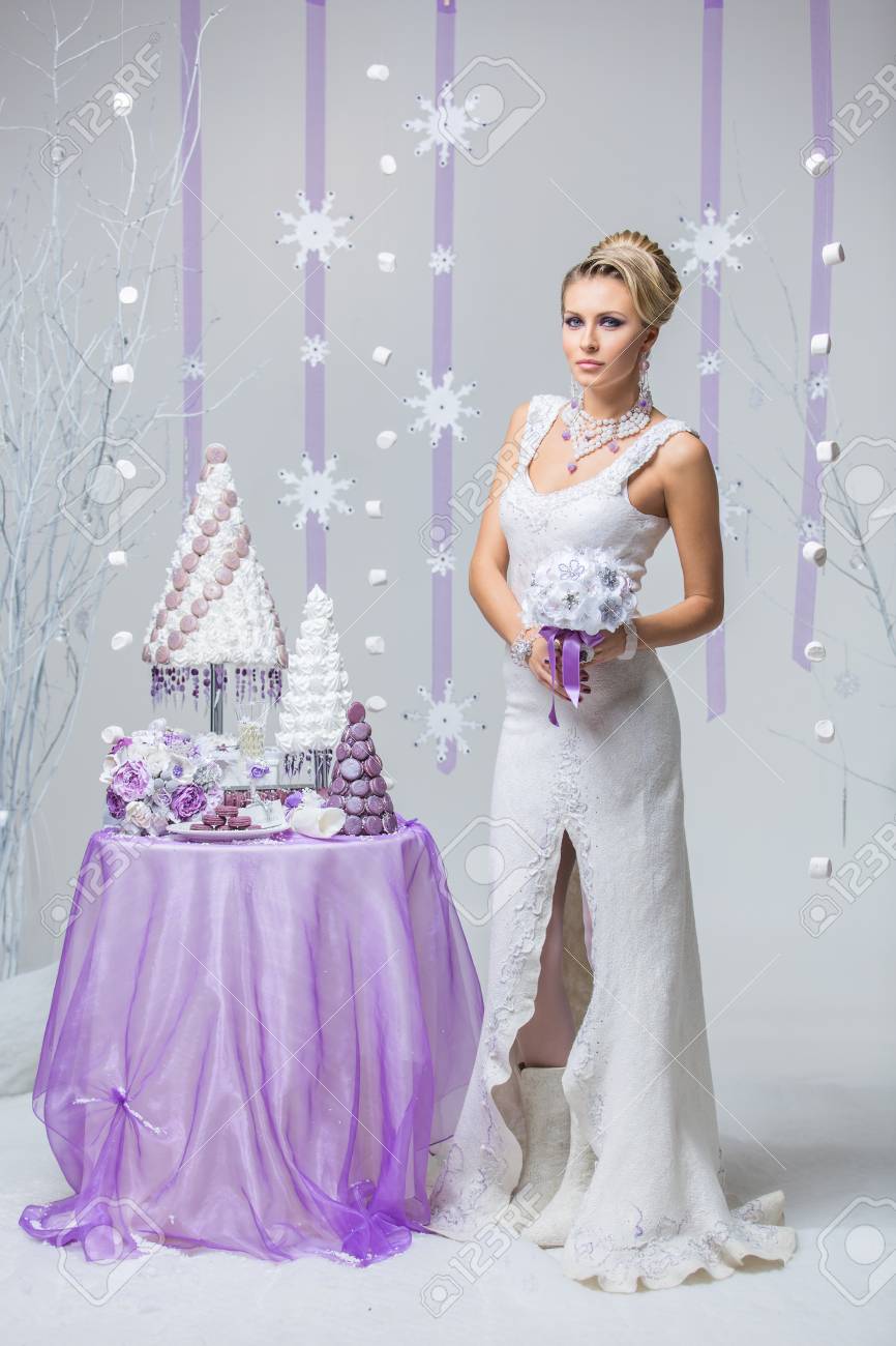 Belle Jeune Femme En Robe De Mariée En Laine Tenant Bouquet De Mariée Debout Près Petite Table Avec Gros Gâteau Croquembouche De Mariage Hiver Mariée