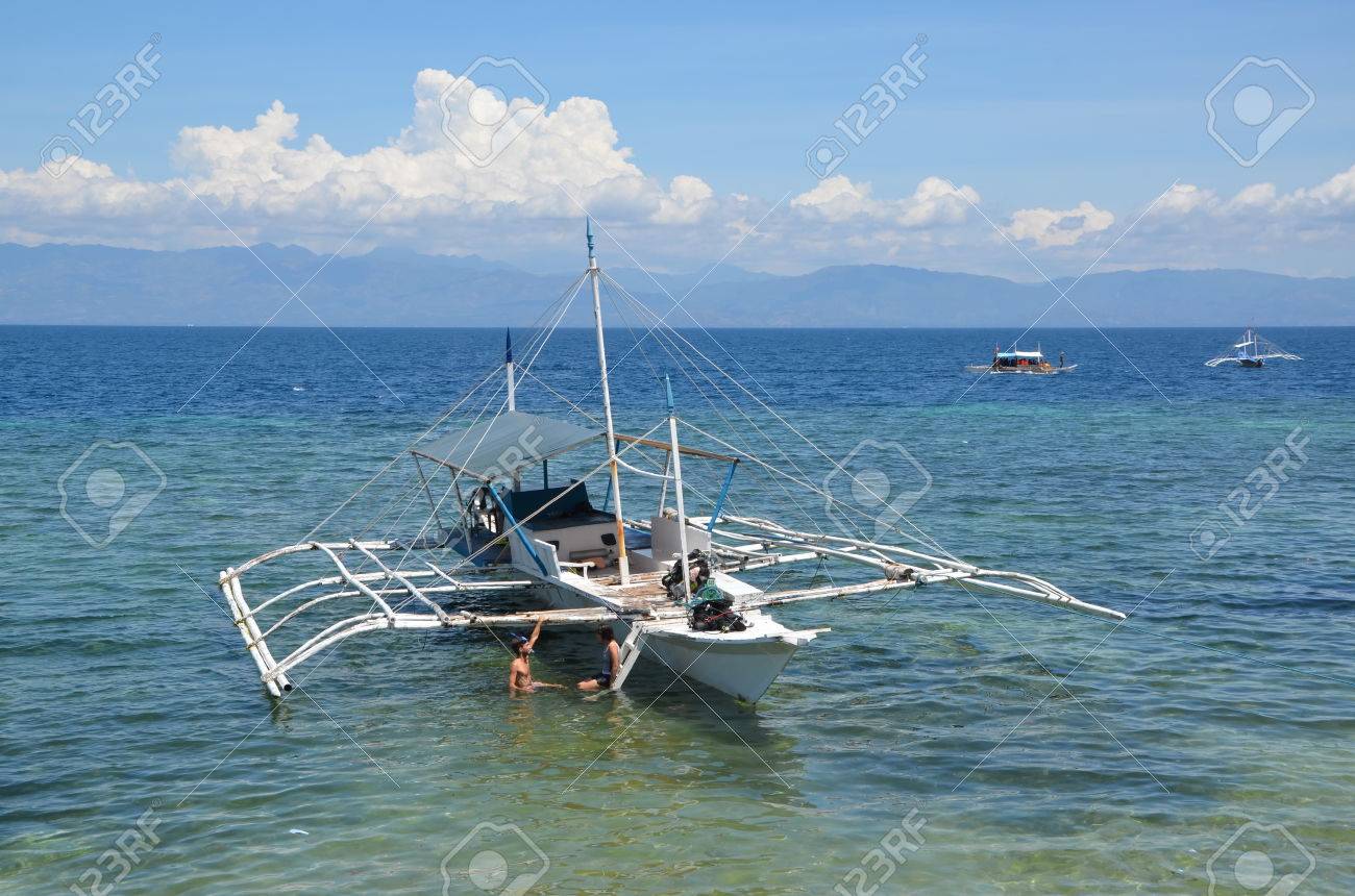 young couple at bangka boat in the ocean in moalboal philippines