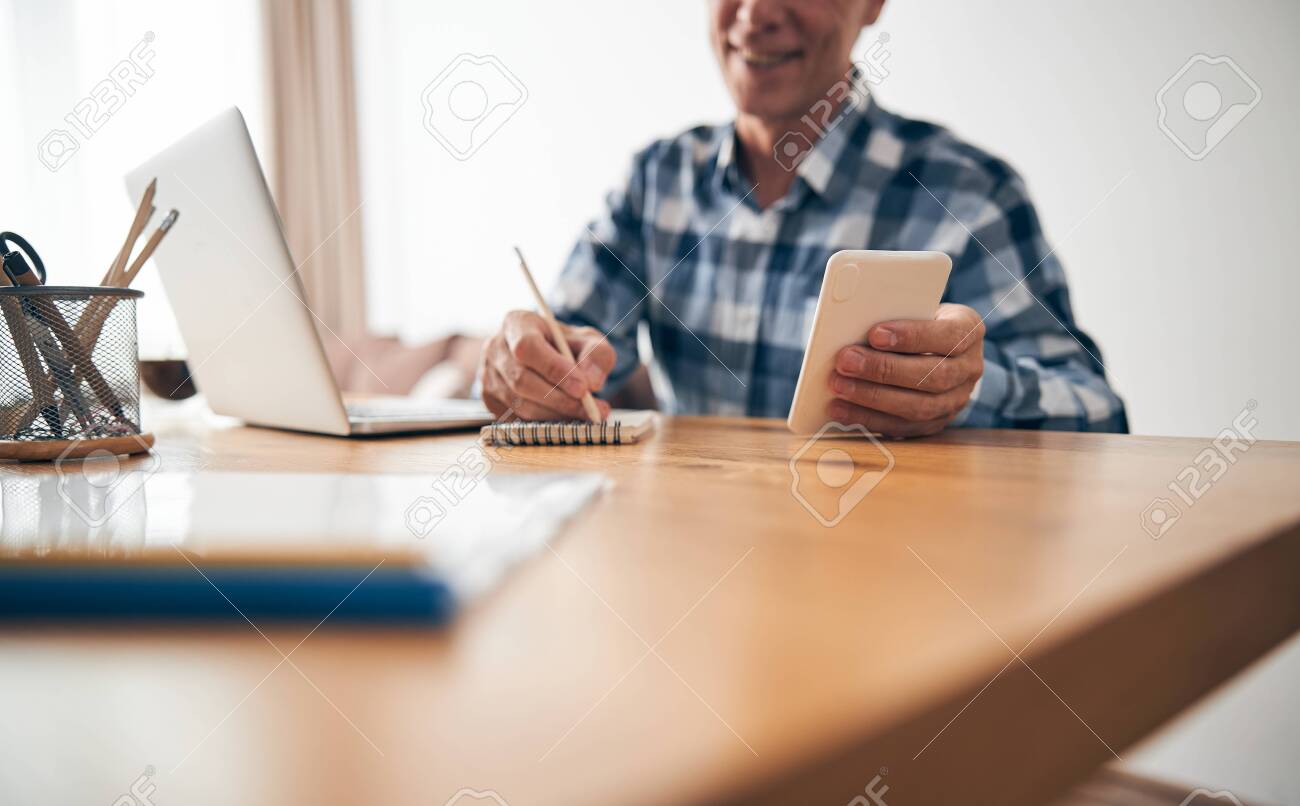 Close up of pleased man making notes - 150448489 Close up of pleased man making notes - 150448489
