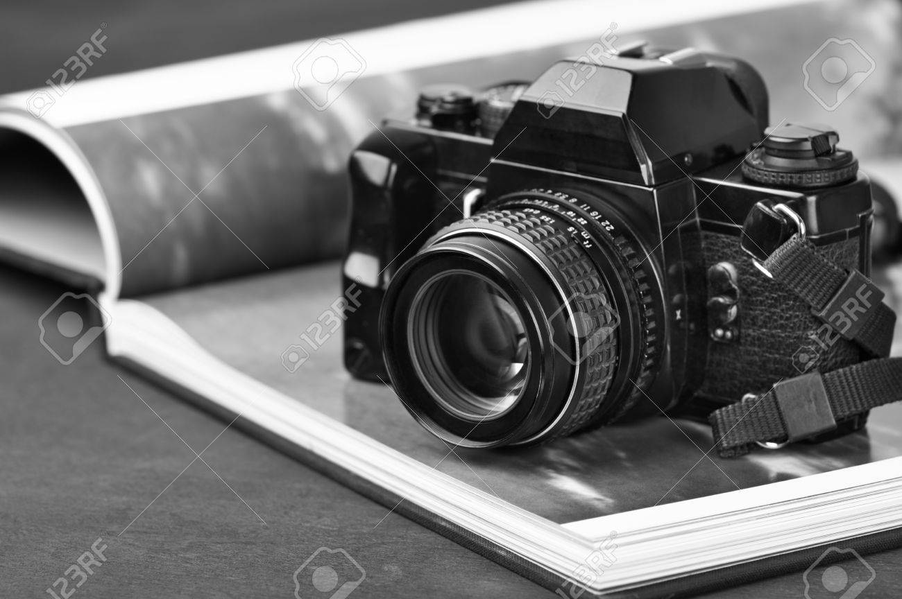 Stock photo vintage mechanical 35mm film photo camera slr and photo book with monochrome picture black and white image