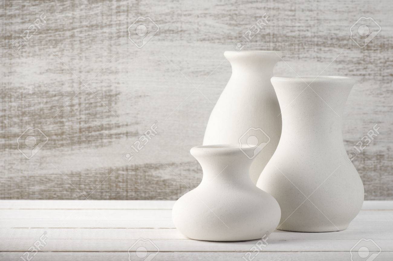 Three Empty White Unglazed Ceramic Vases On White Wooden Table