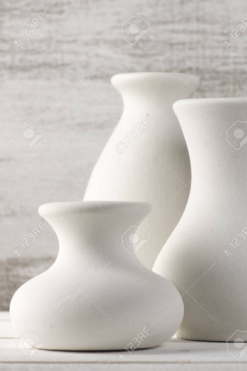Three Empty White Unglazed Ceramic Vases On White Wooden Table