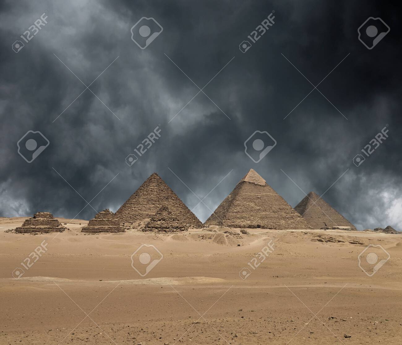 The Giza pyramid complex, or the Giza Necropolis on the Giza Plateau in Egypt near Cairo includes the Great Pyramid of Giza the Pyramid of Khafre and the Pyramid of Menkaure under dramatic grey stormy sky. Composite image. - 142812703 The Giza pyramid complex, or the Giza Necropolis on the Giza Plateau in Egypt near Cairo includes the Great Pyramid of Giza the Pyramid of Khafre and the Pyramid of Menkaure under dramatic grey stormy sky. Composite image. - 142812703