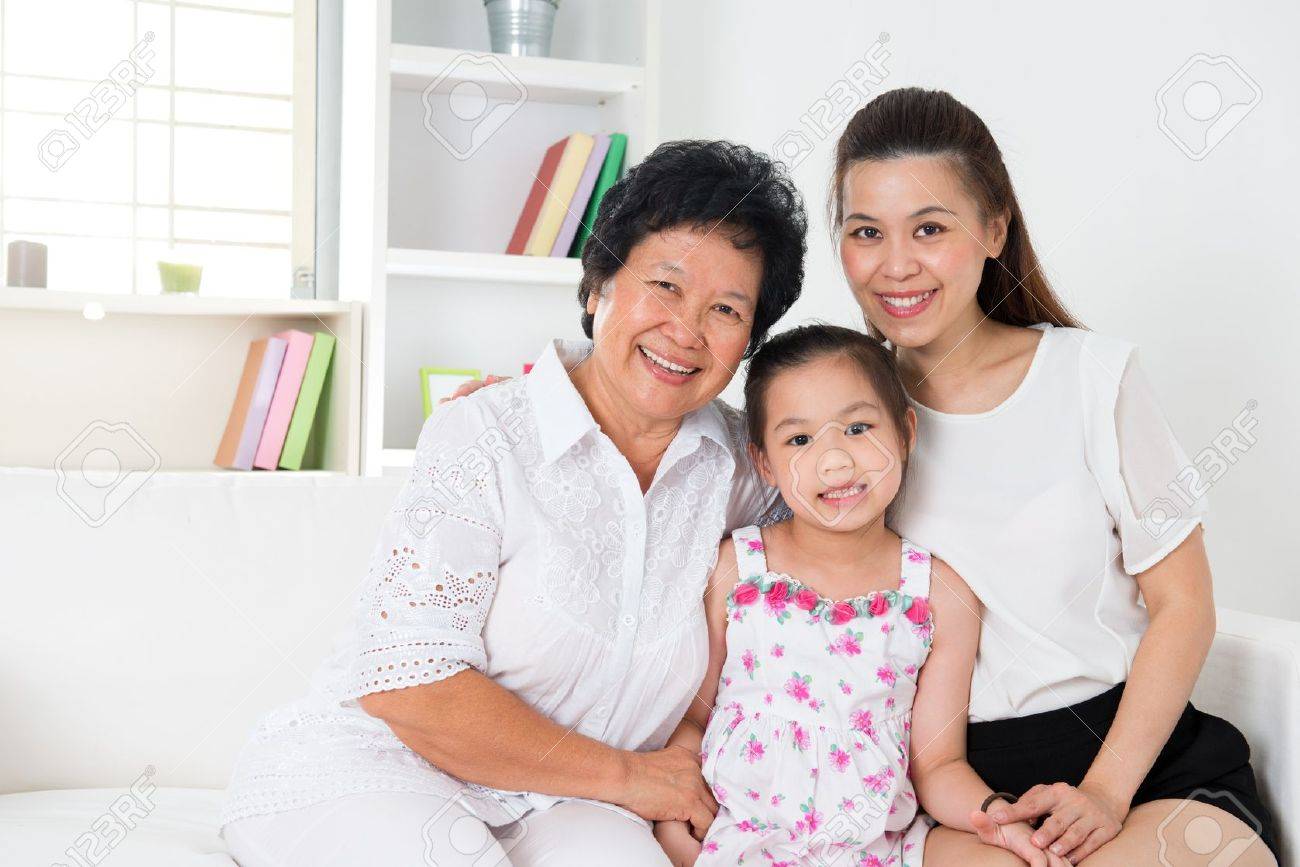 grandparent parent and grandchild sitting on sofa smiling stock