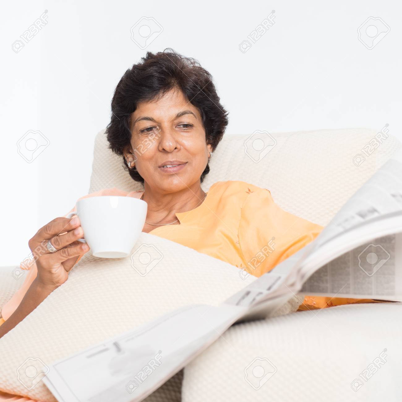 50 の肖像インド熟女新聞を読むと 家でコーヒーを飲みます 屋内高齢者生活のライフ スタイル の写真素材 画像素材 Image