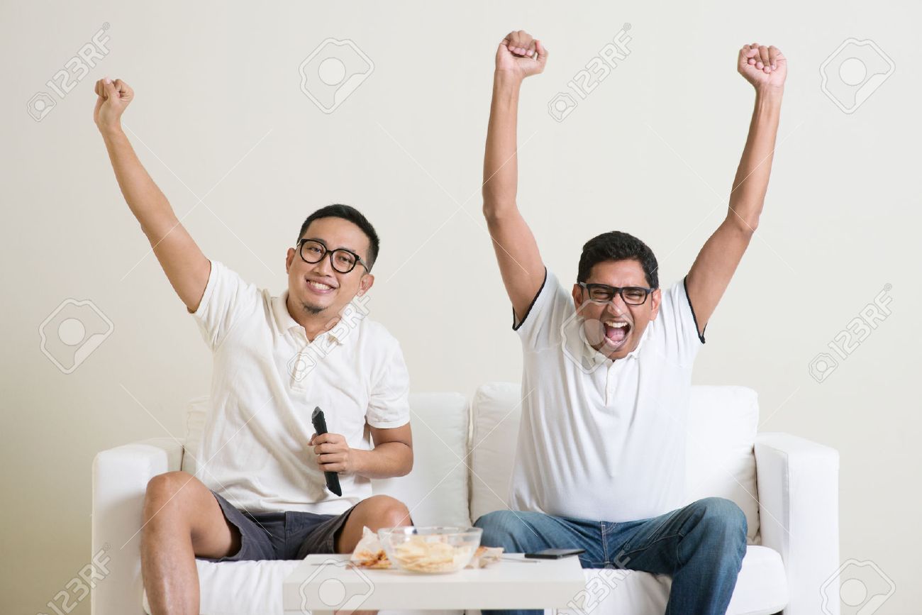 Cheerful group of friends watching football game on tv at home. - 50680663 Cheerful group of friends watching football game on tv at home. - 50680663