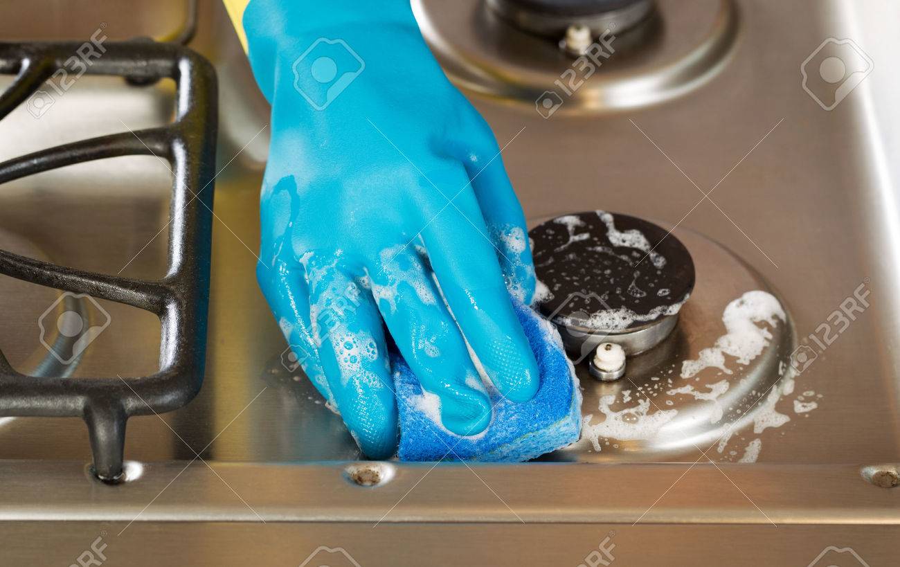 Closeup horizontal image of hand wearing rubber glove while cleaning stove top range with soapy sponge - 29603973 Closeup horizontal image of hand wearing rubber glove while cleaning stove top range with soapy sponge - 29603973