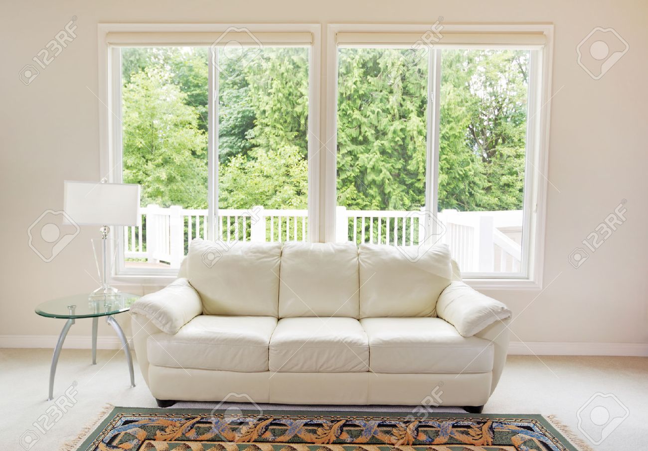 Design Window Couch clean family room with white leather couch and large windows showing bright green trees in background