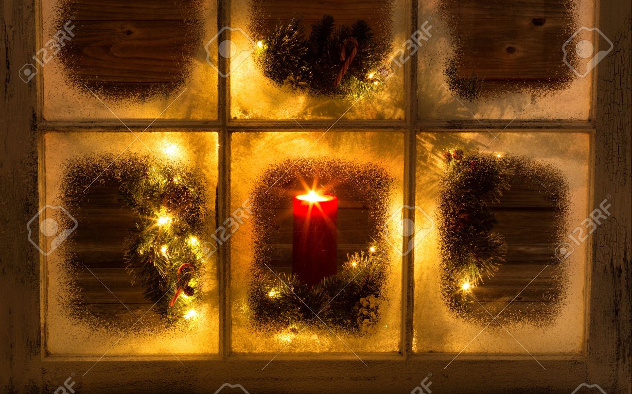 Snow covered window with glowing candle and decorative Christmas wreath on window with rustic wood in background. - 42355620 Snow covered window with glowing candle and decorative Christmas wreath on window with rustic wood in background. - 42355620