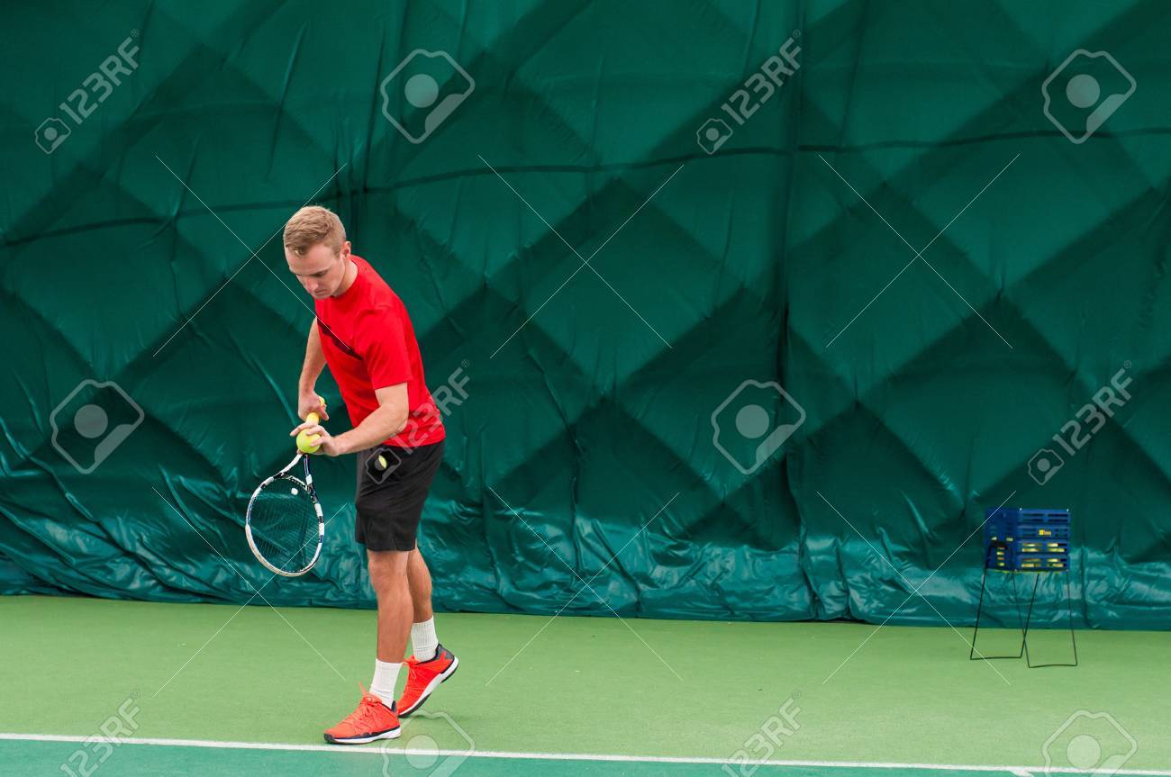 プロのテニス プレーヤーを提供します テニス サーブ テニス ホールの屋内 テニス ラケットに身を包んだ赤い T シャツ 黒パンツと赤い靴とサーブの男 の写真素材 画像素材 Image