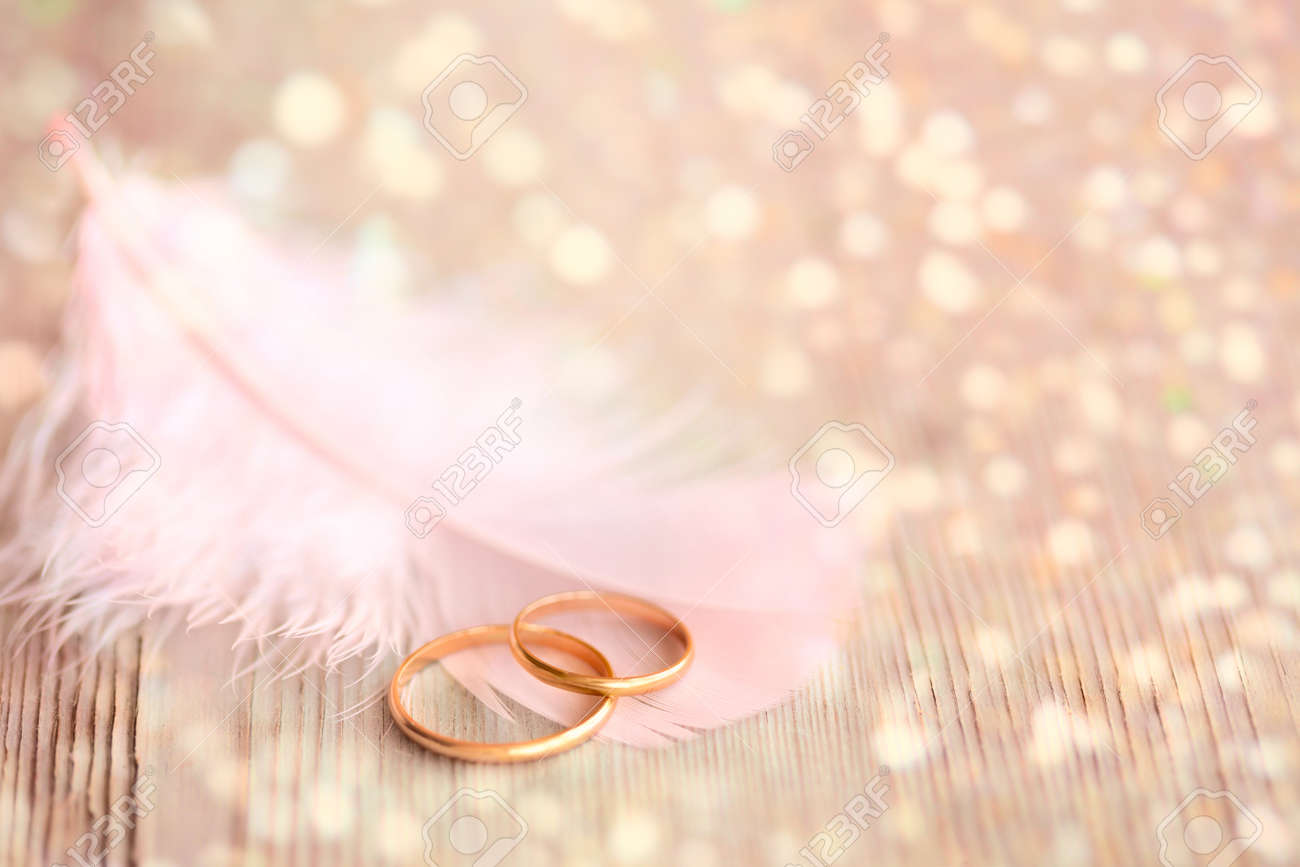 wedding background with gold rings pink feather and golden wedding backgrond