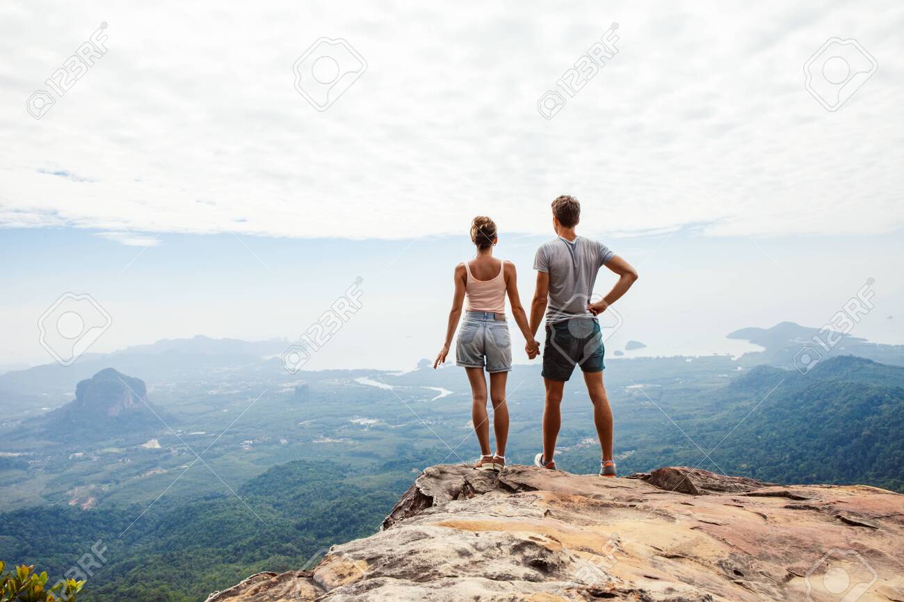 Young couple travelers relaxing on top of a mountain and enjoying the view. Travel concept. - 121749941 Young couple travelers relaxing on top of a mountain and enjoying the view. Travel concept. - 121749941