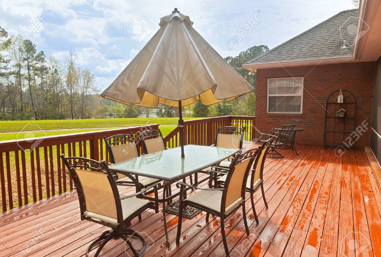 Large wooden backyard deck with patio furniture and a view of lake - 22283818 Large wooden backyard deck with patio furniture and a view of lake - 22283818