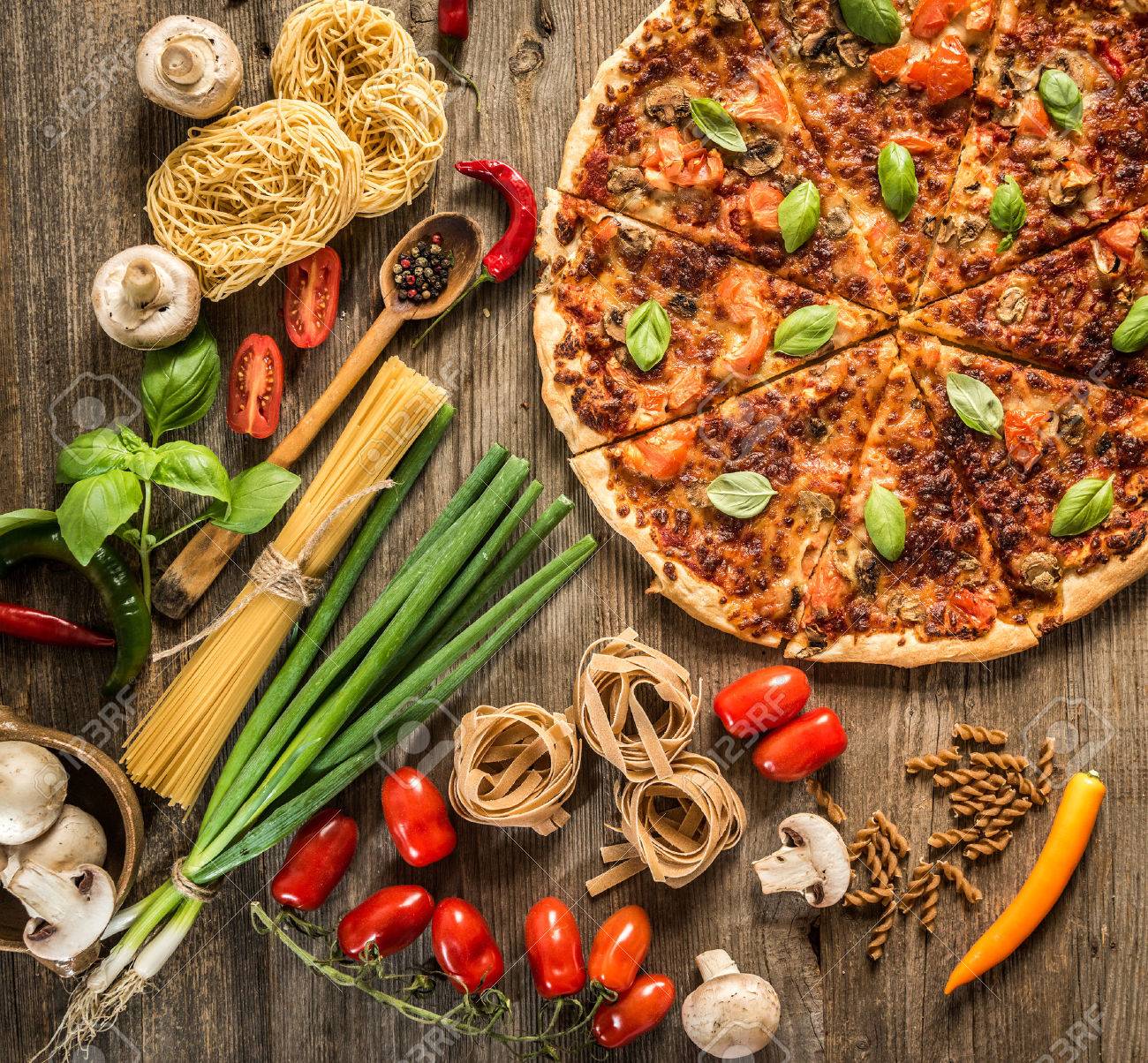 Italian food background with pizza, raw pasta and vegetables on wooden table - 41510281 Italian food background with pizza, raw pasta and vegetables on wooden table - 41510281