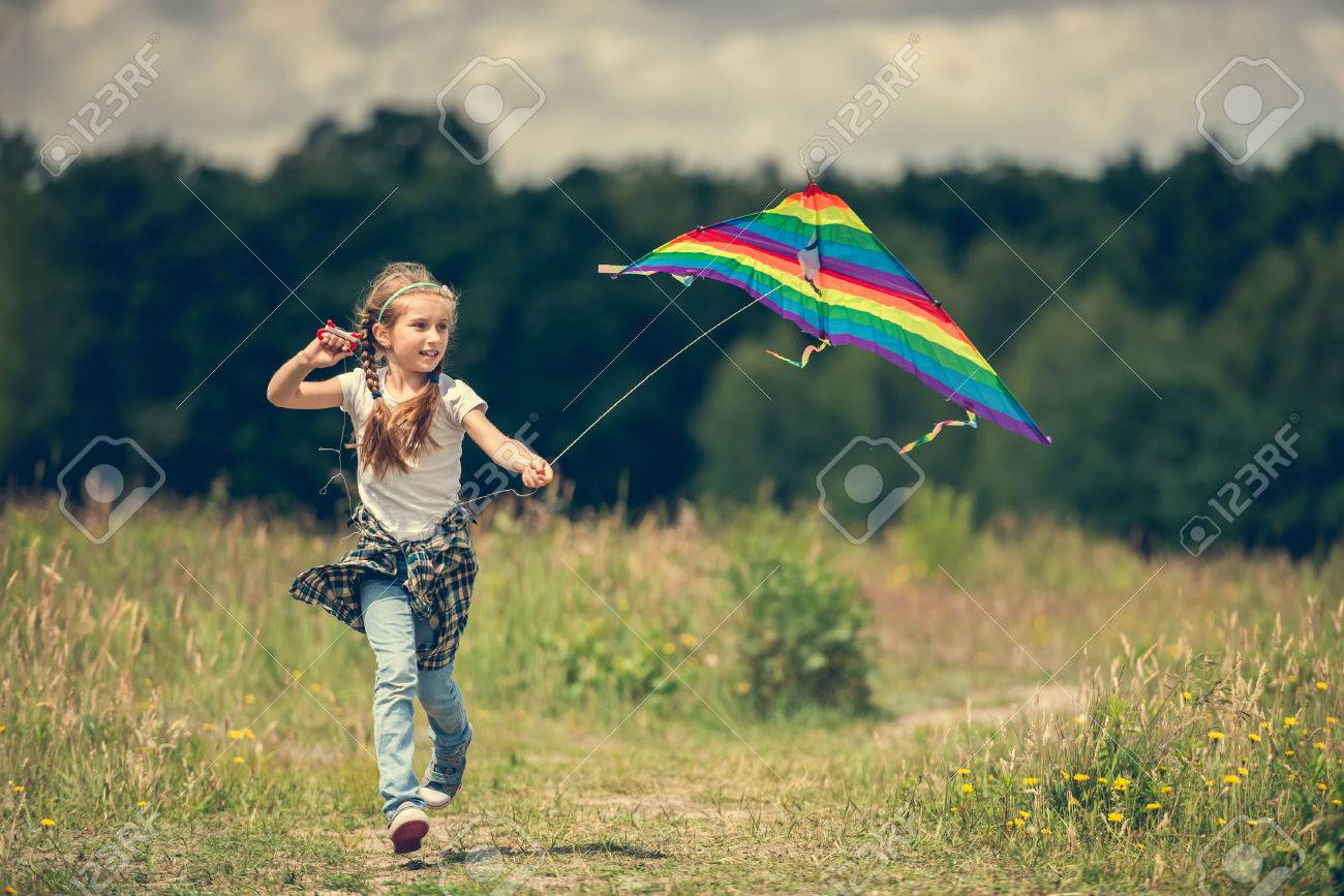little cute girl flying a rainbow kite in a meadow on a sunny day - 44481343 little cute girl flying a rainbow kite in a meadow on a sunny day - 44481343