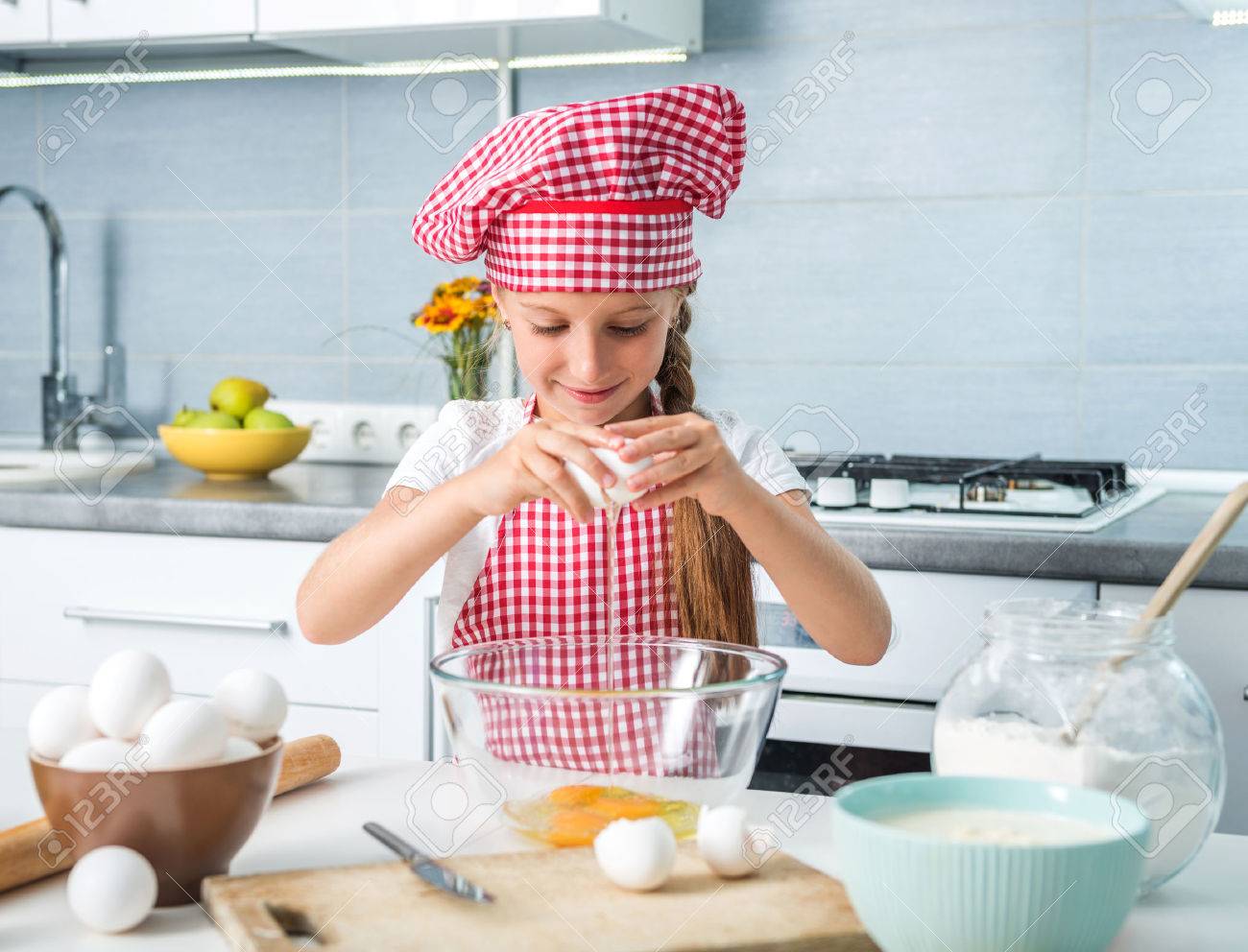 little girl breaking eggs into a glass bowl preparing a dough - 50818466 little girl breaking eggs into a glass bowl preparing a dough - 50818466