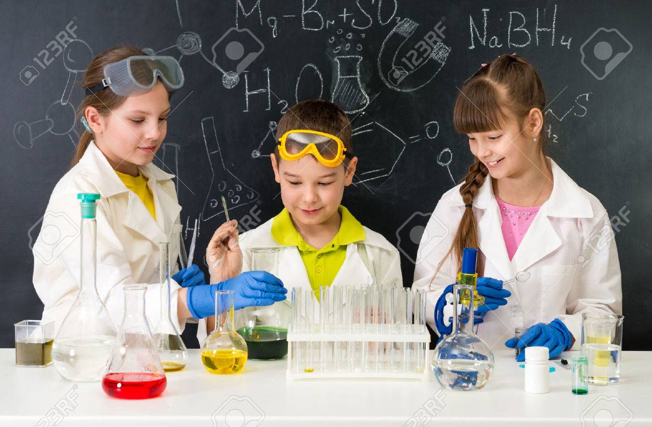 three little students on chemistry lesson in lab doing an experiment - 57342040 three little students on chemistry lesson in lab doing an experiment - 57342040