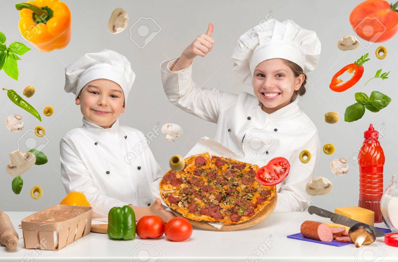 little boy and girl in white uniform of chef by the table with flying pizza - 57342546 little boy and girl in white uniform of chef by the table with flying pizza - 57342546