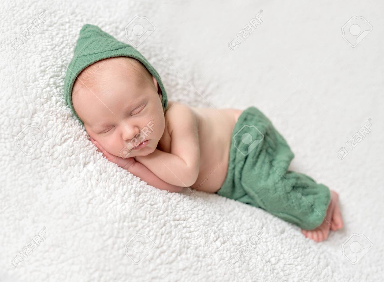 cute newborn sleeping in green elf hat and panties stock photo