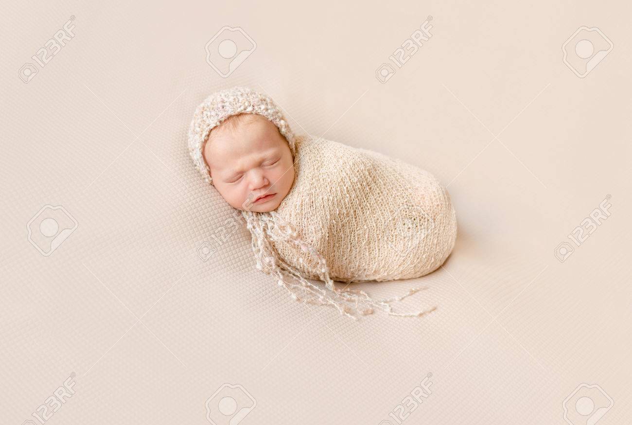lovely wrapped baby in hat sleeping on a beige blanket - 68566121 lovely wrapped baby in hat sleeping on a beige blanket - 68566121