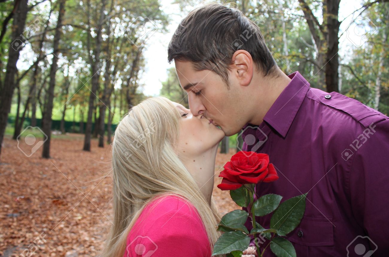 Young Boy Kissing Young Beautiful Girl With Rose Stock Photo.