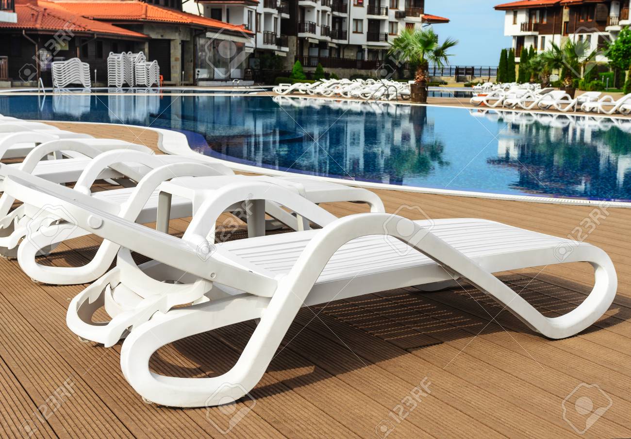 White Plastic Chaise Lounges By The Pool. Close-up. Stock Photo - White Plastic Chaise Lounges By The Pool. Close-up. Stock Photo