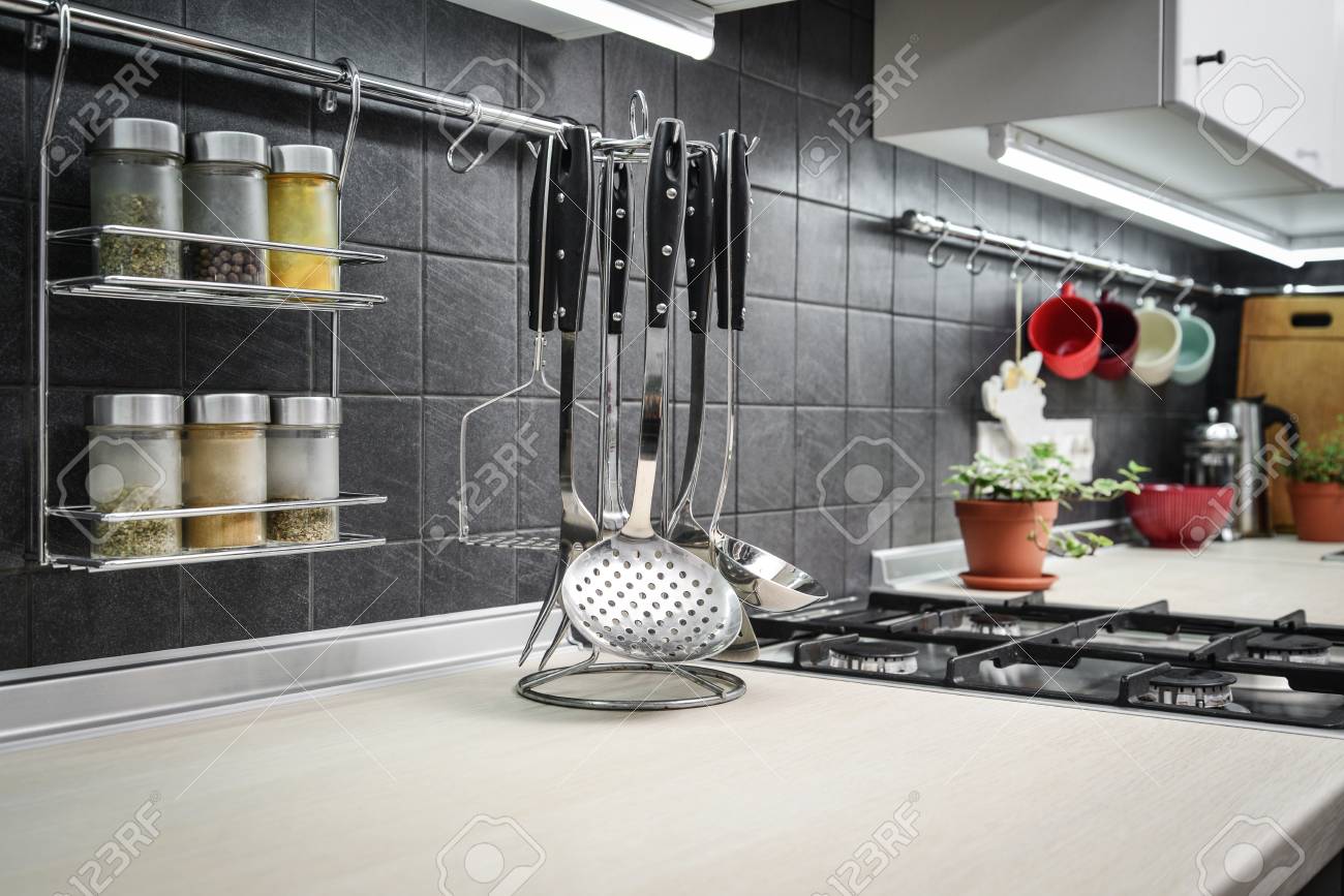Kitchen Utensils And Jars Of Spices In Hanging Shelf In Modern
