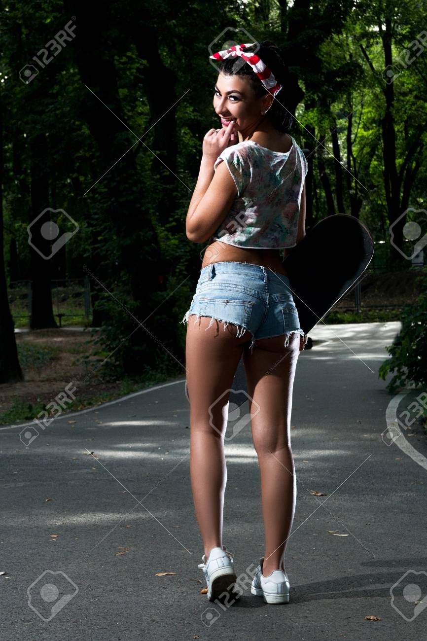 Chica Con Estilo Y Atractiva En Pantalones Cortos Eróticos Caminando En El Parque Un Monopatín En Las Manos Fotos, Retratos, Imágenes Y Fotografía Archivo Libres De Derecho. Image 73190324.