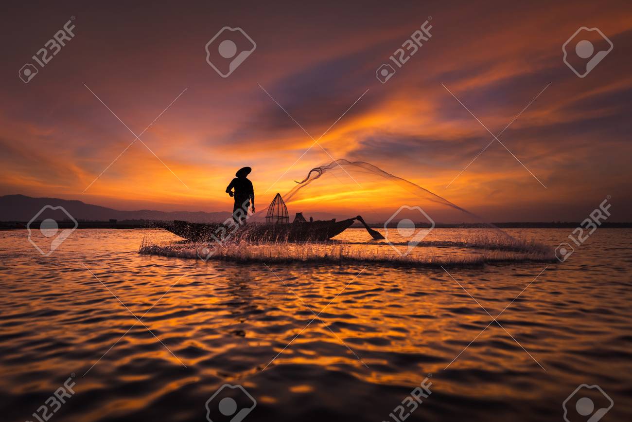 投網を日の出前に早朝自然川の淡水魚をキャッチするための木製のボートに乗ってアジア漁師のシルエット の写真素材 画像素材 Image