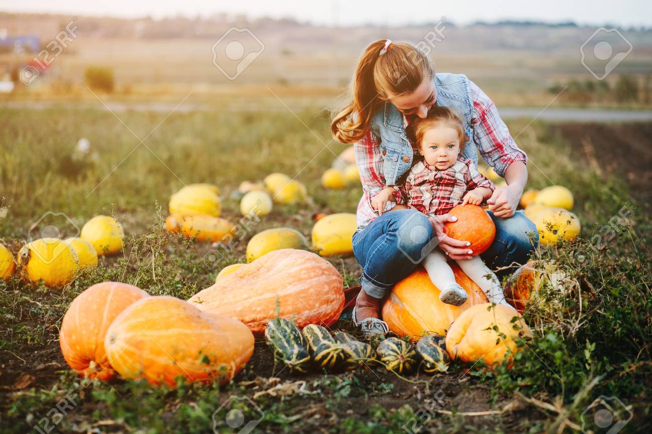 Mother and daughter sitting on pumpkins, Halloween eve - 62636679 Mother and daughter sitting on pumpkins, Halloween eve - 62636679