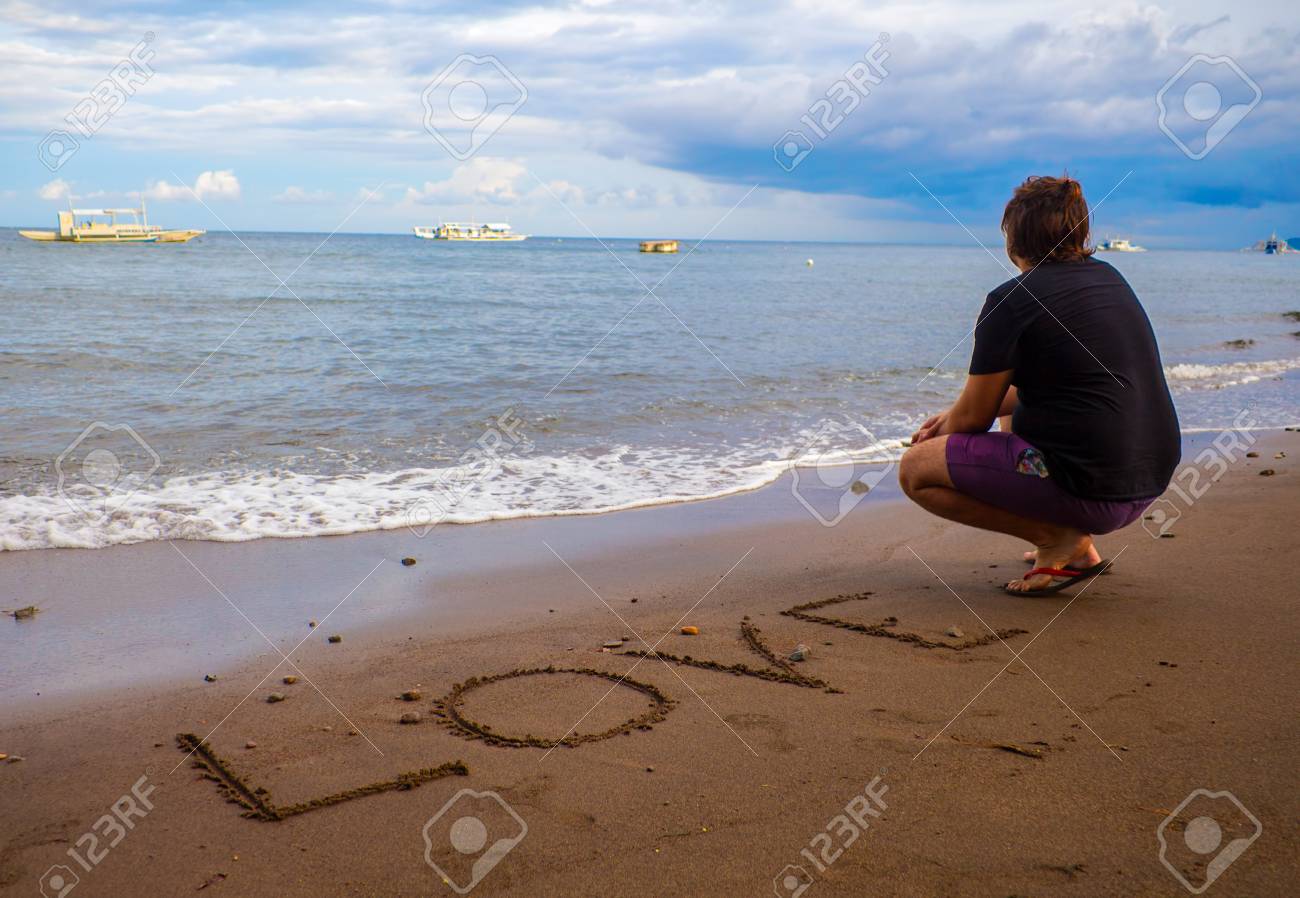 inscription love on the sand empty beach with a man in black